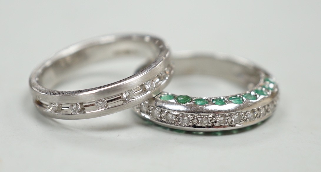 An unusual modern 18ct white gold and thirteen stone diamond chip set half hoop ring, each side of the settling set with ten emeralds, size L and one other modern 18ct white gold and diamond chip set ring, size N, gross